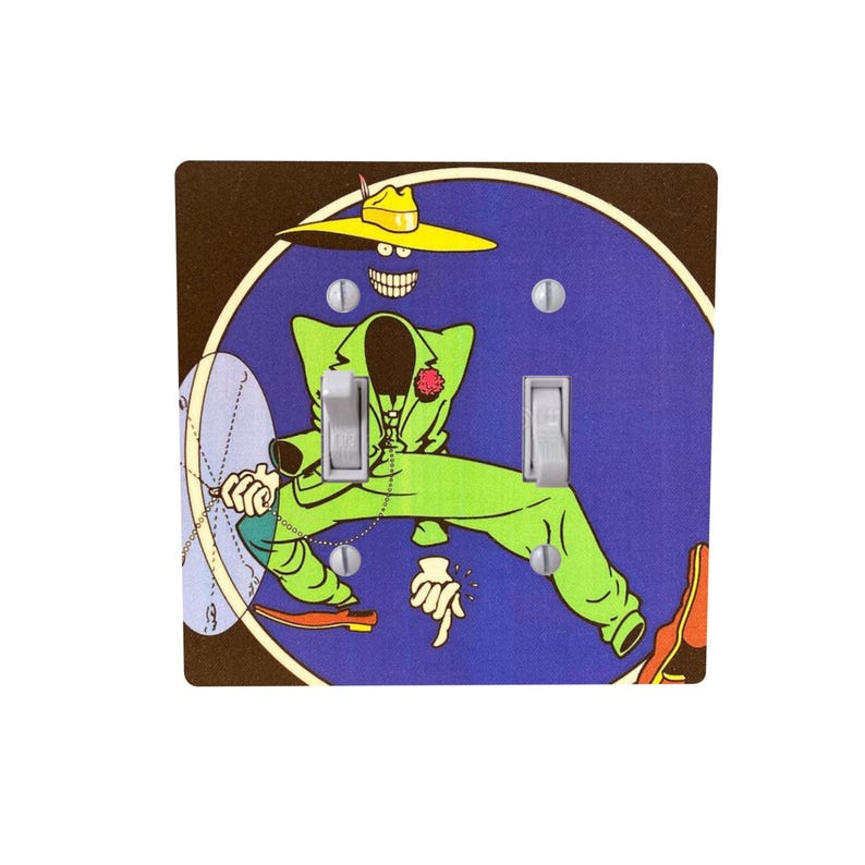 Peut inclure: Plaque d&eacute;corative pour interrupteur avec un personnage de dessin anim&eacute; en costume vert et chapeau jaune sur fond bleu. Le personnage a un large sourire et tient un microphone. La plaque a deux bascules d'interrupteur.