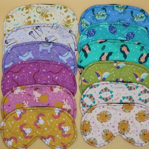 May include: Set of 10 colorful sleep masks featuring different zodiac signs. Each mask is made of soft fabric and has a unique design.