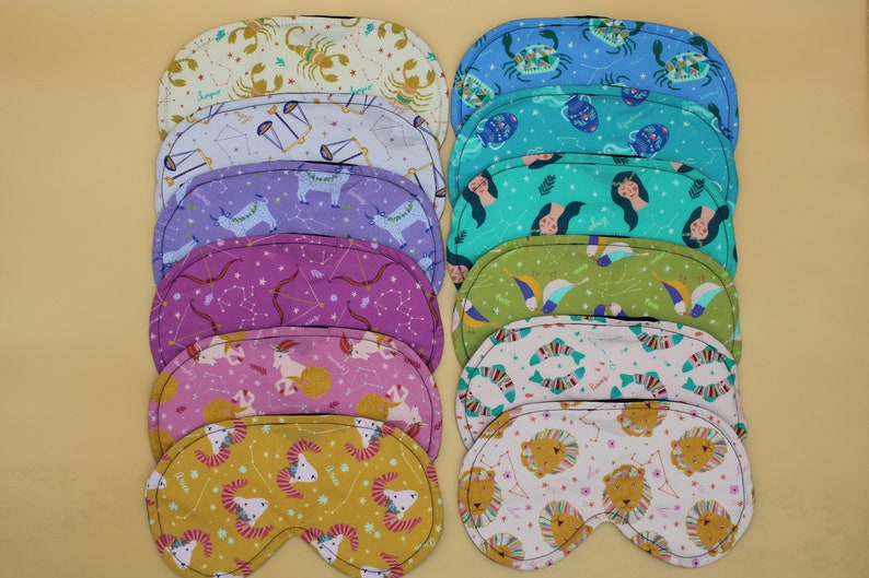 May include: Set of 10 colorful sleep masks featuring different zodiac signs. Each mask is made of soft fabric and has a unique design.