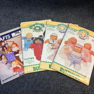 May include: Four sewing pattern envelopes for Cabbage Patch Kids dolls. One McCall's Crafts pattern 746 and three Butterick patterns featuring illustrations of dolls in various outfits, including dresses, pajamas, and hats, with printed text and logos.