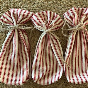 May include: Three red and white striped fabric gift bags tied with twine.