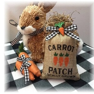 Pode incluir: Uma caneca de cerâmica branca com uma alça preta e o texto "But first, coffee" em preto, com uma fonte manuscrita. A caneca está sobre uma superfície branca.