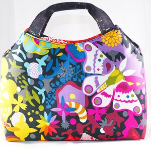 May include: A colorful tote bag with a black background and a butterfly pattern. The bag has a black handle and is made of fabric.