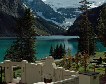 May include: A white stone building with a fireplace and a view of a lake and snow-capped mountains in the background.
