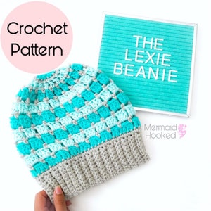 Può includere: Un berretto all'uncinetto fatto a mano con un motivo a scacchiera, con sfumature di turchese, azzurro e grigio. Il cappello ha un bordo grigio a coste. Il testo sull'immagine recita "Crochet Pattern" e "The Lexie Beanie".
