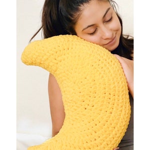 May include: A yellow crocheted crescent moon shaped pillow.