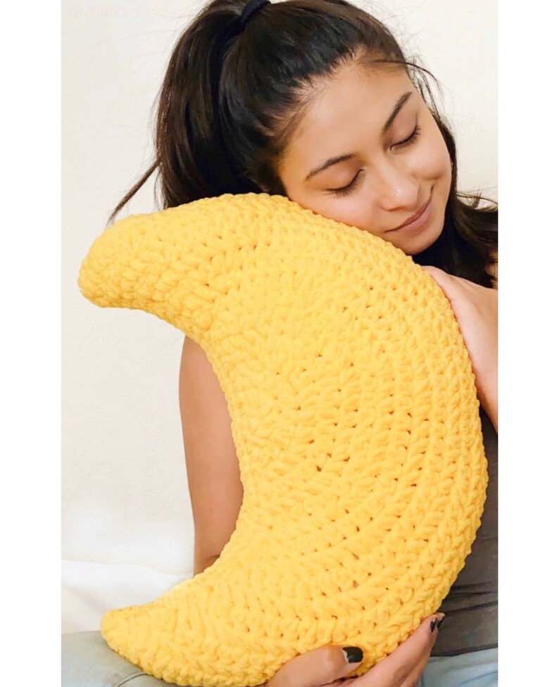 May include: A yellow crocheted crescent moon shaped pillow.