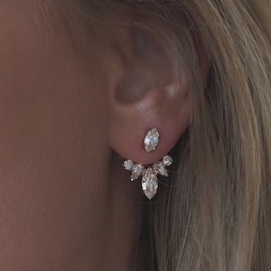 Puede incluir: Pendientes de oro con un racimo de cristales transparentes en forma de lágrima. Los pendientes están diseñados para llevarse en el lóbulo superior de la oreja y tienen un pequeño cristal de tachuela en el lóbulo inferior.