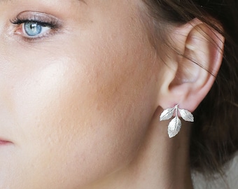May include: Silver leaf earrings with a delicate design. The earrings are small and feature three leaves each.