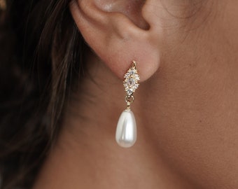 May include: Gold dangle earrings with a pearlescent teardrop pendant and clear crystal accents.