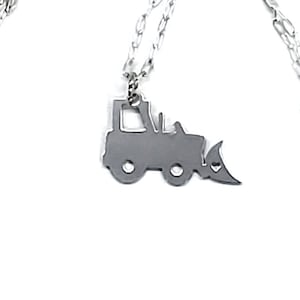 May include: A silver necklace with a silver bulldozer pendant. The chain is a delicate, linked chain.