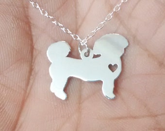 May include: A silver-colored pendant necklace featuring a dog silhouette with a heart-shaped detail. The dog pendant is attached to a delicate chain. The necklace is displayed against a neutral background.