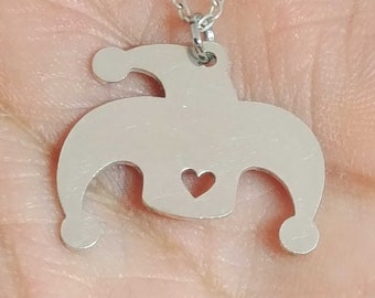 May include: A silver necklace with a pendant shaped like a jester's hat with a small heart cut out in the center.