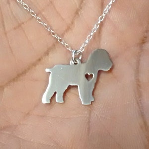 May include: A silver necklace with a pendant shaped like a dog with a heart cut out of its chest.