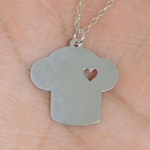 May include: A silver necklace with a pendant shaped like a cross with a heart cut out of the center.