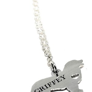 May include: Silver necklace with a dog-shaped pendant. The pendant is engraved with the name "GRIFFEY".