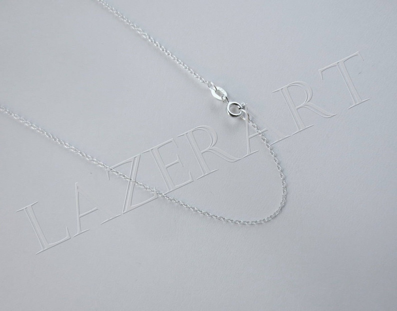 May include: A silver chain necklace with a lobster clasp closure. The chain is on a white background with the word "LAZERART" printed on it.