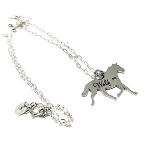 May include: Silver necklace with a horse pendant. The pendant has the word "Wolf" engraved on it and a small heart cutout.