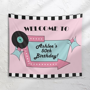 May include: Pink birthday banner with a retro design. The banner reads "Welcome to Ashlee's 50th Birthday!" in black and teal lettering. A black and white checkered border frames the top and bottom.