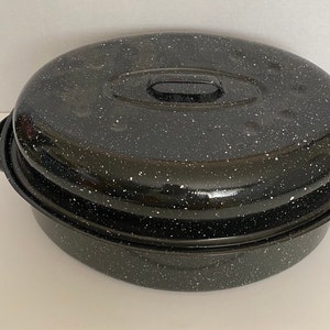 May include: Black enamel oval roaster with a lid. The roaster has a speckled finish and a handle on each side.