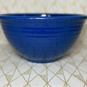 May include: A vibrant blue ceramic bowl with a glossy finish. The bowl has a wide, rounded shape with a textured, ridged exterior. The bowl is likely for serving or mixing food.
