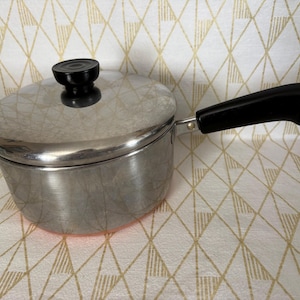 May include: A set of three ceramic mugs with a speckled, matte finish. The mugs are in shades of cream, light brown, and dark brown. Each mug has a simple, minimalist design and a rounded handle.