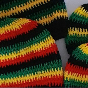Puede incluir: Cuatro gorros de ganchillo en rayas negras, verdes, rojas y amarillas. Los gorros est&aacute;n hechos con un hilo grueso y tienen una superficie texturizada.