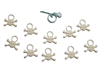 May include: Ten white plastic skull charms with a ring at the top. The charms are scattered on a white background.