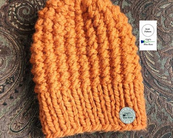 May include: A bright orange knitted beanie hat with a brown leather tag that says "Gigg's Blue Rose" and "Knit Pattern".