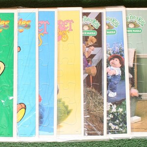 May include: A set of eight 25-piece children's jigsaw puzzles featuring characters from the shows "The Wizzles" and "Patch Kids". The puzzles are packaged in plastic and have colorful illustrations.