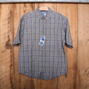 May include: A short-sleeved plaid button-down shirt in shades of gray, blue, and red. The shirt has a standard collar and a button-up front.