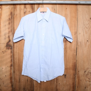 May include: A light blue short-sleeved button-down shirt with a white collar and white buttons.