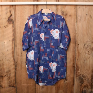 May include: A blue short-sleeved shirt with a geometric and floral pattern in shades of blue, white, and orange.