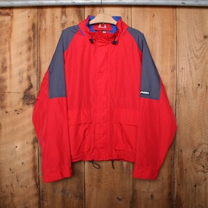 May include: A red, blue, and black windbreaker jacket with a zipper closure and a drawstring at the waist. The jacket has a logo on the right sleeve that says "SPIDEN".