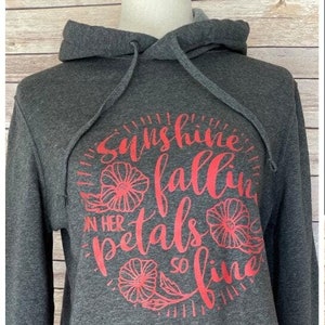 May include: A dark gray hooded sweatshirt with a red graphic print that says "Sunshine fallin' on her petals so fine".