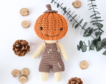 Puede incluir: Una muñeca de calabaza de ganchillo con un mono marrón. La muñeca tiene una cara sonriente y está hecha con hilo naranja, marrón y beige.