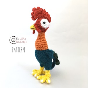 May include: Crocheted rooster toy with a red comb, orange body, teal blue chest, and yellow feet. The rooster has a white eye with a black pupil.