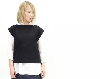 May include: A woman wearing a black sleeveless top over a white button-down shirt, a dark blue denim wrap skirt, and brown sandals.