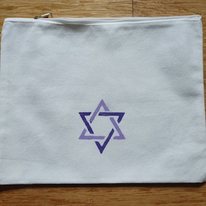 Op de afbeelding: Witte canvas toilettas met een geborduurde Davidster in paars en blauw aan de voorkant.