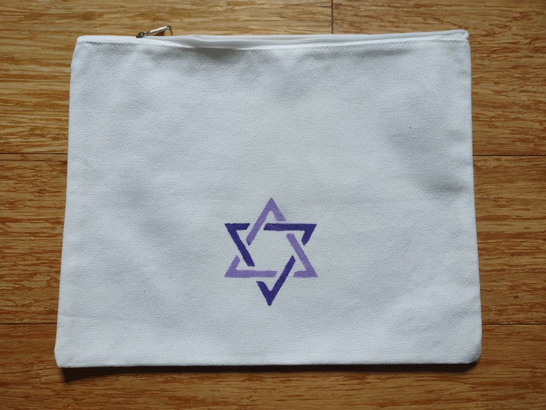 Op de afbeelding: Witte canvas toilettas met een geborduurde Davidster in paars en blauw aan de voorkant.
