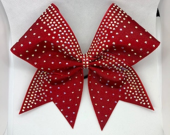 May include: A large red cheer bow with a sparkly, iridescent design. The bow is decorated with clear rhinestones.