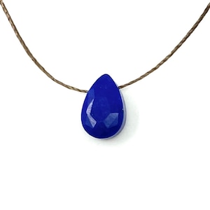 May include: A blue gemstone pendant necklace with a teardrop-shaped stone on a brown cord.