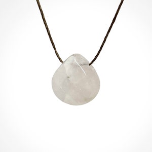 May include: A delicate, teardrop-shaped pendant made of clear, pale pink quartz, hanging from a brown cord.
