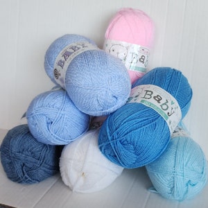 May include: A collection of yarn balls in various shades of blue and white, with one pink ball. The yarn balls have labels that say "Baby Big Value Gift".