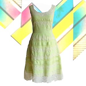 May include: A sleeveless, light green dress with white lace trim and detailing. The dress features a scoop neckline and a fitted bodice that flares into a full skirt. The dress is made of a lightweight fabric, perfect for warm weather.