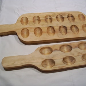 May include: Two wooden egg molds with handles. The larger mold has 18 indentations and the smaller mold has 8 indentations.