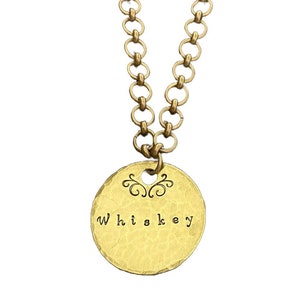 May include: A gold-toned necklace with a round charm that says "Whiskey" in a cursive font. The charm has a decorative swirl design above the word.