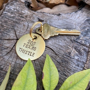 May include: A gold-colored key chain with a round tag that says "205 Texas Thistle" and a gold-colored key with the number "44843" on it.