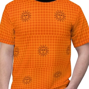 Puede incluir: Camiseta naranja con cuello negro y mangas cortas. La camiseta presenta un patrón repetido de caras de sol con rayos detallados. El fondo tiene un pequeño patrón cuadrado. La camiseta está hecha de un material suave.