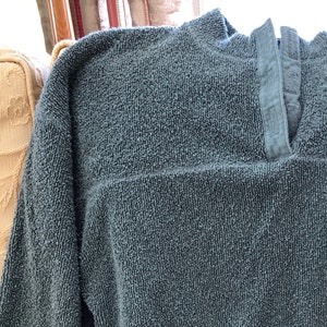 May include: A blue fleece pullover with a mock neck and long sleeves. The pullover has two pockets on the bottom and a zipper at the neck.